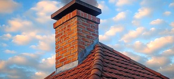 Capped brick chimney drawing a clean line of smoke at dusk
