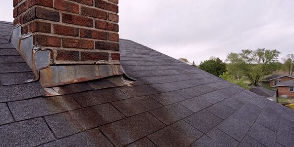 Rust-streaked failing flashing at a chimney base telling on its leak